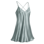 A light sage green mulberry silk slip dress with thin spaghetti straps and a crisscross back, shown on a transparent checkered background.