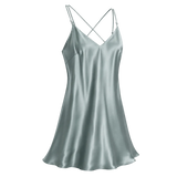A light sage green mulberry silk slip dress with thin spaghetti straps and a crisscross back, shown on a transparent checkered background.