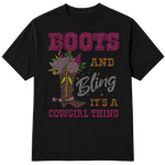 A black short-sleeve t-shirt with a western-themed rhinestone-style graphic that reads 'BOOTS AND Bling IT'S A COWGIRL THING' in pink, gold, and silver lettering, alongside an illustration of a cowboy boot decorated with flowers on a transparent background.