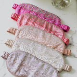 Set of rhinestone eye masks with rhinestone embellishments on a marble surface.