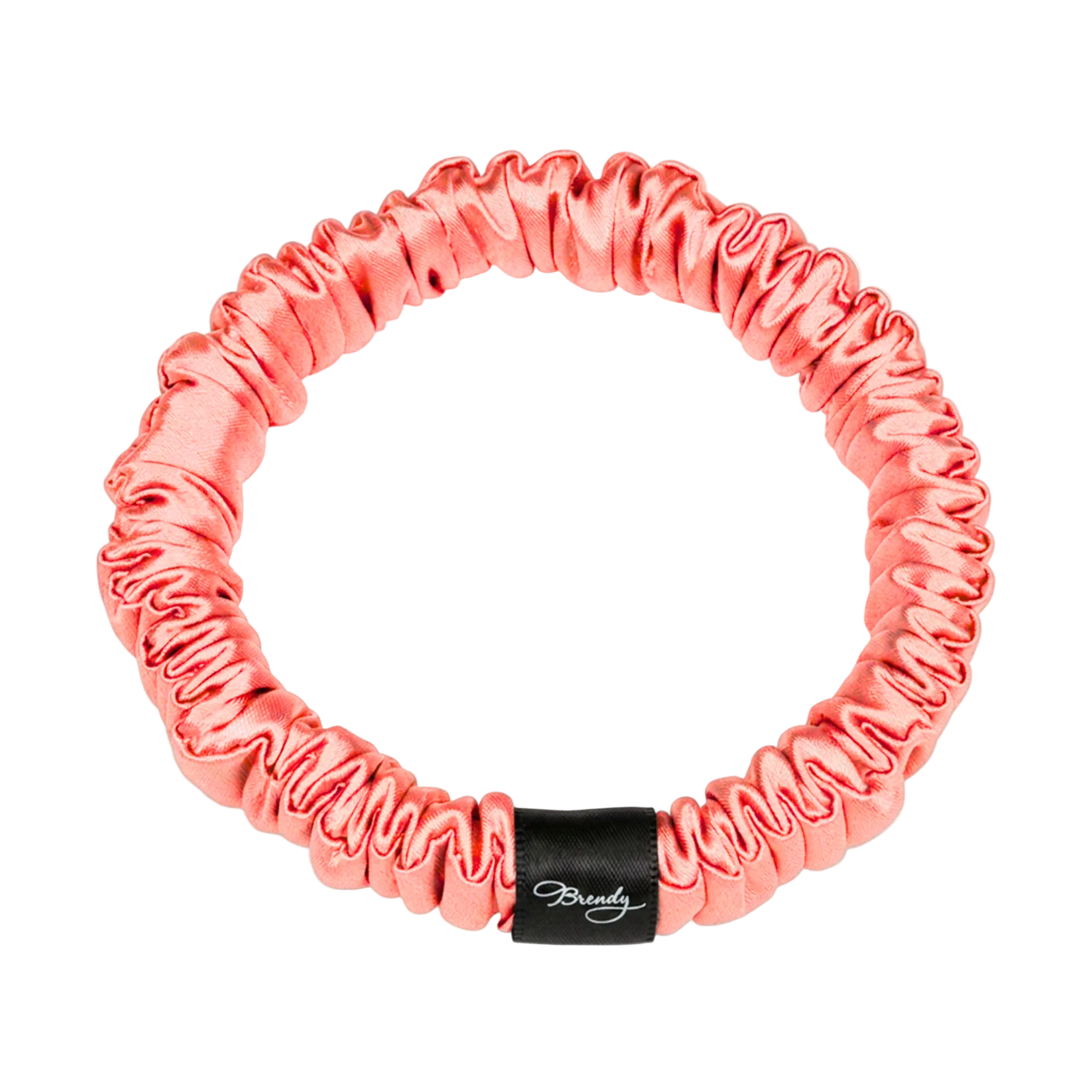 Coral skinny silk scrunchie with a black Brindy Label on a white background