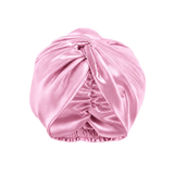 A  cotton candy pink mulberry silk turban-style hair cap with a gathered ruched center and elasticized bottom, shown on a transparent checkerboard background.