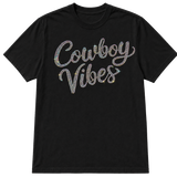 A black short-sleeve crewneck t-shirt featuring the words 'Cowboy Vibes' in a cursive script embellished with AB sparkling rhinestones that reflect multiple colors, shown on a transparent background.
