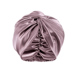 A dusty mauve mulberry silk turban-style headwrap or bonnet with gathered ruching and an elasticized bottom, shown on a transparent checkerboard background.