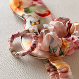 Peach floral scrunchies and sleep mask on a textured surface