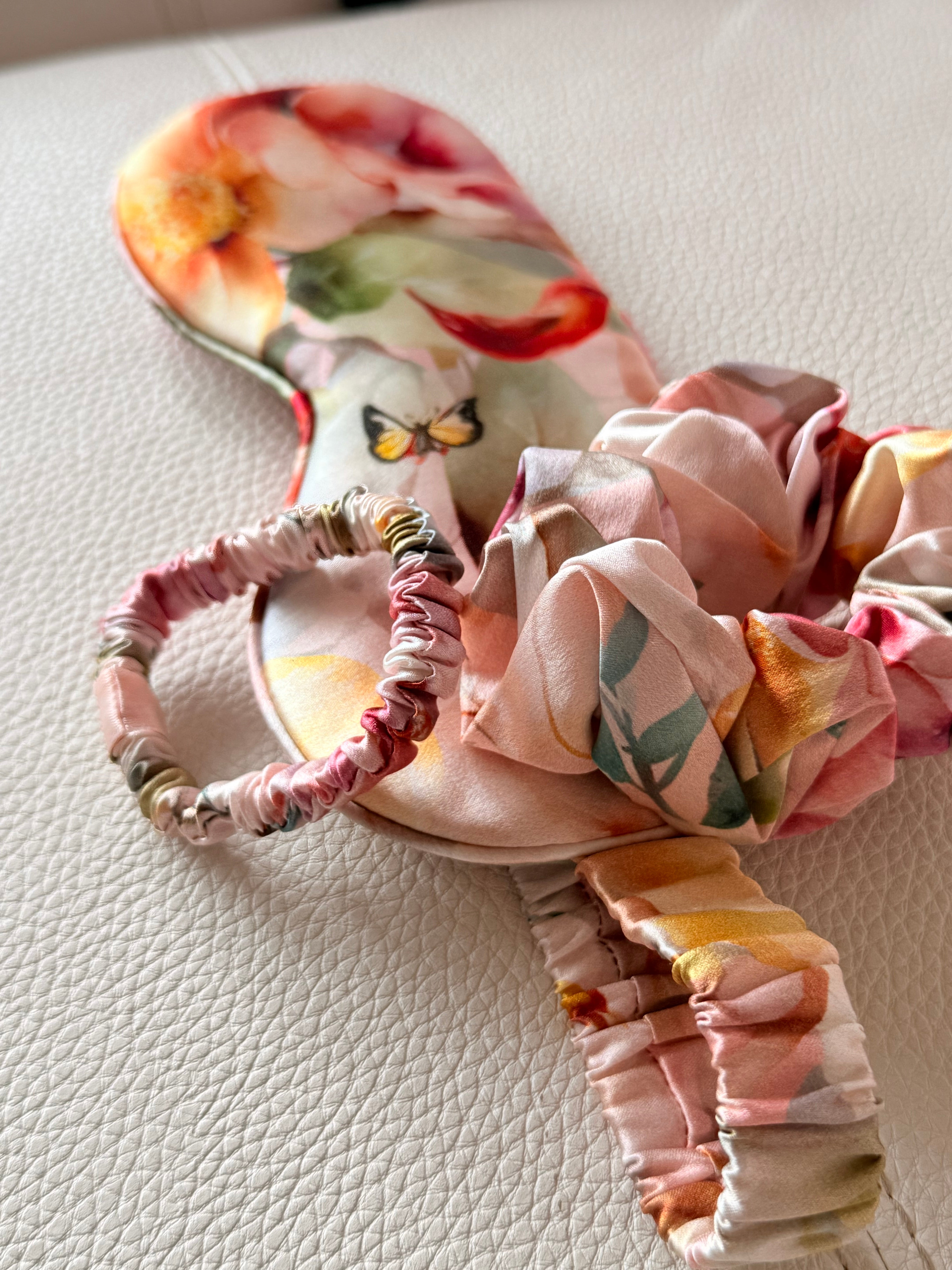 Peach floral scrunchies and sleep mask on a textured surface