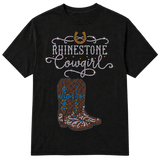 A black short-sleeve t-shirt with a rhinestone-style graphic on the front featuring a horseshoe, the words 'RHINESTONE Cowgirl' in white script, and a pair of cowboy boots in brown, blue, and white rhinestones on a transparent background.