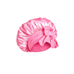 A candy pink mulberry silk bonnet with a large bow on a transparent background.
