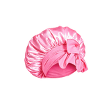 A candy pink mulberry silk bonnet with a large bow on a transparent background.